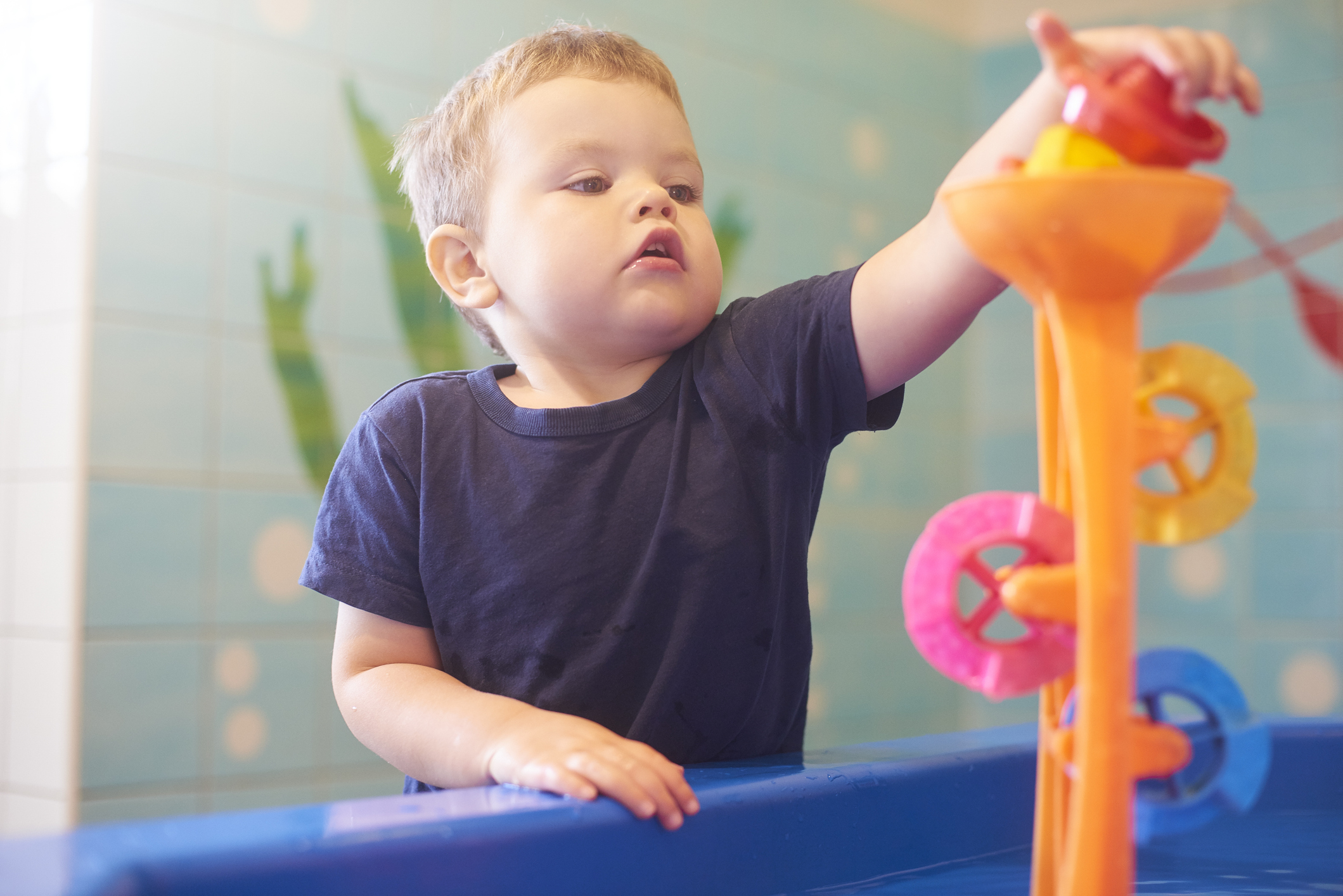 Toddler interacting with toys and educational equipment at nursery or children’s museum